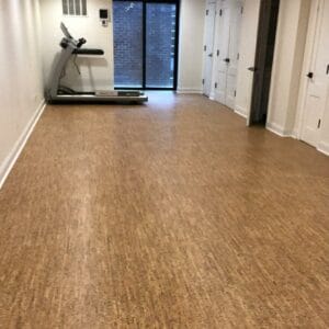 Home fitness room with natural cork flooring and a treadmill near sliding glass doors.